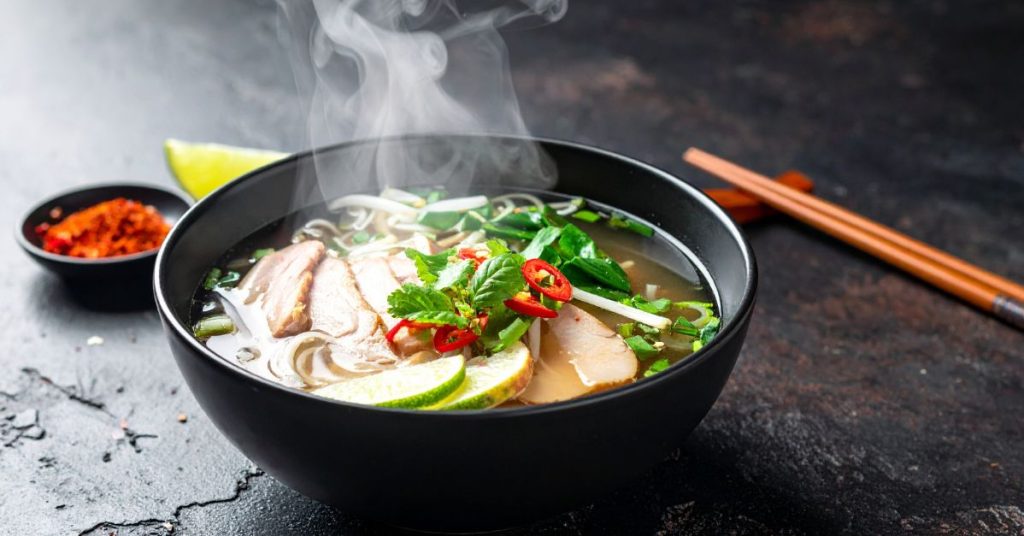 How Do You Eat Pho? Tips for Enjoying Vietnam’s National Dish Close-up of garnishes like lime, herbs, and chilli on a pho bowl.